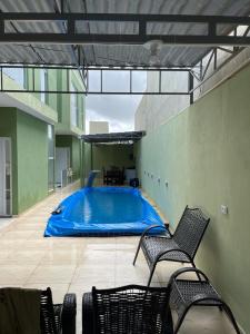 圣若泽-达科罗阿格兰迪Casa 3 Quartos, 2 suites, piscina e sossego的一座带两把椅子的建筑中的游泳池