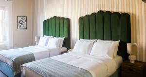 伦敦The Columbia的配有绿色床头板的酒店客房内的两张床