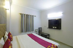 新德里Airport KINGDOM的卧室配有一张床,墙上配有电视。
