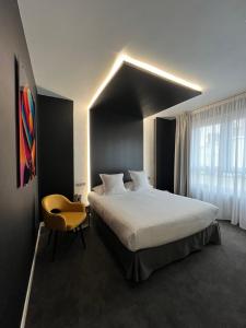 敦刻尔克LOGIS Hôtel Borel的一间卧室配有一张大床和一张黄色椅子