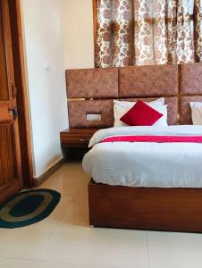 西姆拉The White House Shimla的一间卧室配有一张带红色枕头的大床