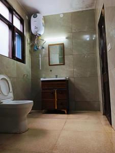 西姆拉The White House Shimla的一间带卫生间、水槽和镜子的浴室