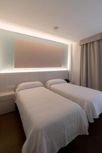 瓦伦西亚爱卡塔酒店的配有白色床单的酒店客房内的两张床