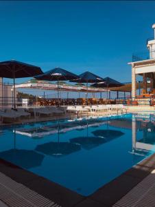 巴尔El Mar Hotel的一个带遮阳伞和桌椅的游泳池