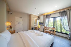 Ban Ru Sa Mi LaeThe Wood Pattani Hotel的卧室设有一张白色大床和大窗户