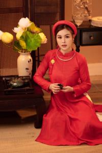 顺化Thuy Duong Boutique Hotel Hue的坐在桌子旁的红色衣服上的女人