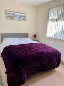 莫克姆Eden Stay的卧室配有床上的紫色毯子