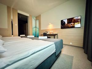 比亚韦斯托克Hotel Turkus的酒店客房设有两张床和一台墙上的电视。
