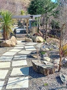 拉腊Clarisses Cottage的石头步道,在种有岩石和树木的花园中