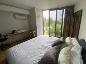 华欣Sanctuary Hua Hin near Khao Takiab beach的一间卧室配有一张床、一张书桌和一个窗户。