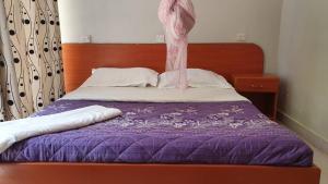 金贾Arise Africa International Christian Guesthouse的一张带紫色棉被和木制床头板的床