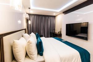 阿布贾BON Hotel Nest Garki II Abuja的卧室配有白色的床和电视。
