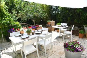 奇斯泰尼诺B&B Masseria Piccola的白色的桌子,配有白色的椅子和盆栽植物