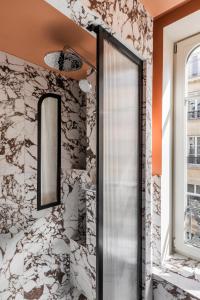 巴黎Hôtel Chamar的浴室设有石墙和玻璃淋浴间。