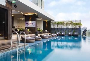 胡志明市自由中心西贡河畔酒店的酒店游泳池设有椅子,酒店大楼