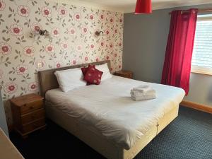 葛特纳格林Hazeldene Hotel的一间卧室配有带白色床单和红色枕头的床。