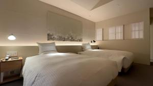 南淡路市安娜加度假酒店的配有白色床单的酒店客房内的两张床