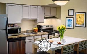 孟菲斯Sonesta Simply Suites Memphis East Poplar Pike的厨房配有白色橱柜和鲜花桌