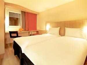 德莱蒙德莱蒙宜必思酒店的酒店客房设有一张白色大床和一张书桌