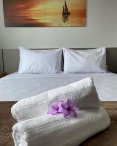 拉巴拉德纳圣米格尔Pousada Cantinho da Barra的白色的床,带一条毛巾,上面有紫色花