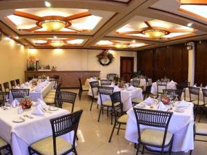 曼巴豪甘米银高地度假酒店的宴会厅配有白色的桌椅