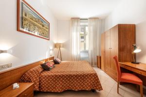 锡耶纳密涅瓦酒店的酒店客房配有一张床、一张书桌和一张书桌。