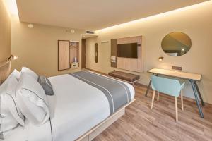 恩塞纳达港City Express Plus by Marriott Ensenada的酒店客房设有一张大床和一张书桌。