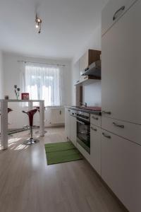 格拉茨Flataid Apartment Elisabethinergasse的厨房配有白色橱柜和绿色地毯。