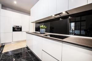 伦敦Premium Belgravia Harrods Apartment的厨房配有白色橱柜和黑色台面