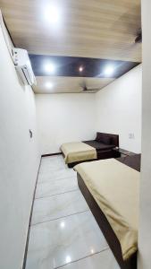 乌贾因HOTEL PRAKASH PALACE的客房设有两张床和一台墙上的电视。
