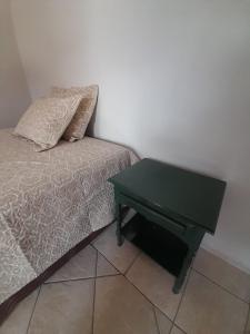 里贝朗普雷托Quarto para temporada的一张带绿桌的床,床边配有枕头