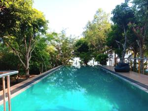 帕讷杜勒Jayaa Villas Bolgoda的拥有蓝色海水和树木的游泳池