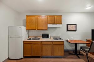 埃尔帕索WoodSpring Suites El Paso的厨房配有木制橱柜和白色冰箱。