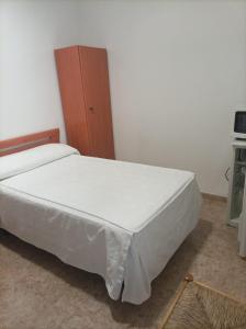 托梅略索PENSIÓN CARLOS III的卧室配有白色的床和木制橱柜。