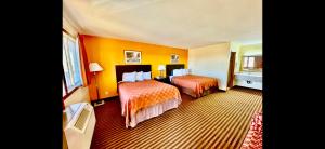 欧克莱尔Scottish Inn & Suites - Eau Claire的酒店客房,设有两张带橙色墙壁的床