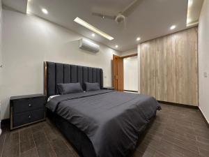 拉合尔Homey Stays - 2 Bedroom Apartment - Gulberg的一间卧室配有一张大床和一个木制橱柜