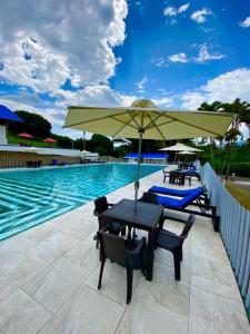 佩雷拉Hotel Villa Mónaco的游泳池旁配有遮阳伞的桌椅