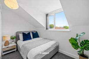 曼彻斯特6 Sarah House by Truestays - 2 Bedroom Apartment - FREE Wifi & Parking的一间卧室配有一张带蓝色枕头的床和一扇窗户。
