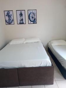 瓜拉派瑞Encanto Guarapari的卧室内的两张床,墙上挂有照片