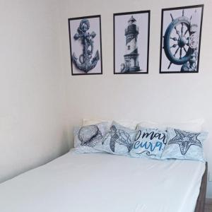 瓜拉派瑞Encanto Guarapari的一张白色的床,墙上挂着四张照片