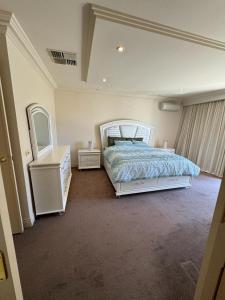 墨尔本Luxurious Townhouse Retreat in Prestigious Brighton的一间卧室配有一张床、梳妆台和镜子