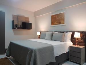 巴雷拉斯Casa dos Belfort的一间卧室配有一张床、两盏灯和一台电视。