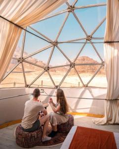 瓦迪拉姆Desert relax camp的坐在窗户房间里的一个男人和女人