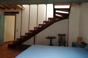 Villanueva del Conde巴图尔卡斯乡村小屋酒店的一间卧室设有一张床和木制楼梯。