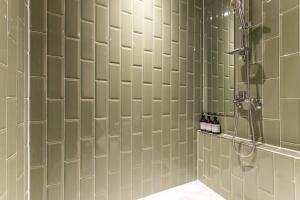 仁川市Brown Dot Hotel Incheon Jakjeon的带淋浴的浴室和绿色瓷砖墙壁