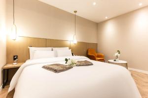 仁川市Brown Dot Hotel Incheon Jakjeon的卧室配有一张白色大床和两把椅子