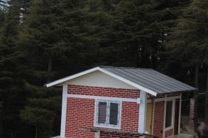 卡纳塔尔The Deodar Stays的一座红白色的小房子,设有太阳能屋顶