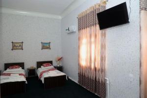 撒马尔罕World Guest House的客房设有两张床和一台平面电视。