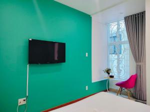 胡志明市Adventure Hotel的一间设有绿色墙壁和平面电视的客房