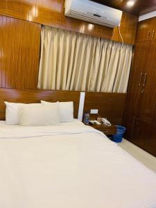 达卡The Castle Inn的卧室配有一张白色大床和木制床头板